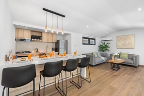 Une cuisine moderne dotée d’un îlot central, de tabourets de bar et d’un coin repas.