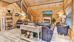 Un intérieur en bois comprenant un canapé, des fauteuils, une table basse, une cheminée et un escalier.