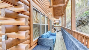 Une cabane en rondins dotée d’un porche couvert, de murs en bois et d’un coin salon avec des coussins.