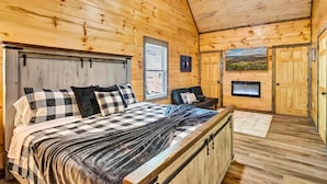 Une chambre à coucher dans un chalet en bois, avec un lit, un banc, une cheminée et une porte donnant sur un paysage pittoresque.