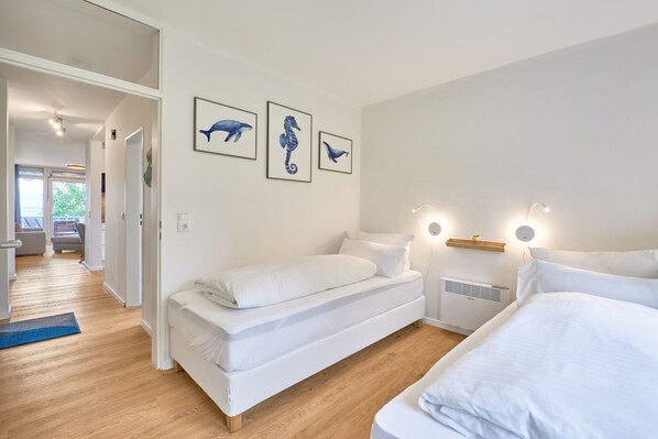 A modern bedroom with a bed, bedside tables, and wall art.