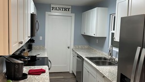Una cocina con gabinetes blancos, un refrigerador de acero inoxidable, un lavamanos y una estufa.