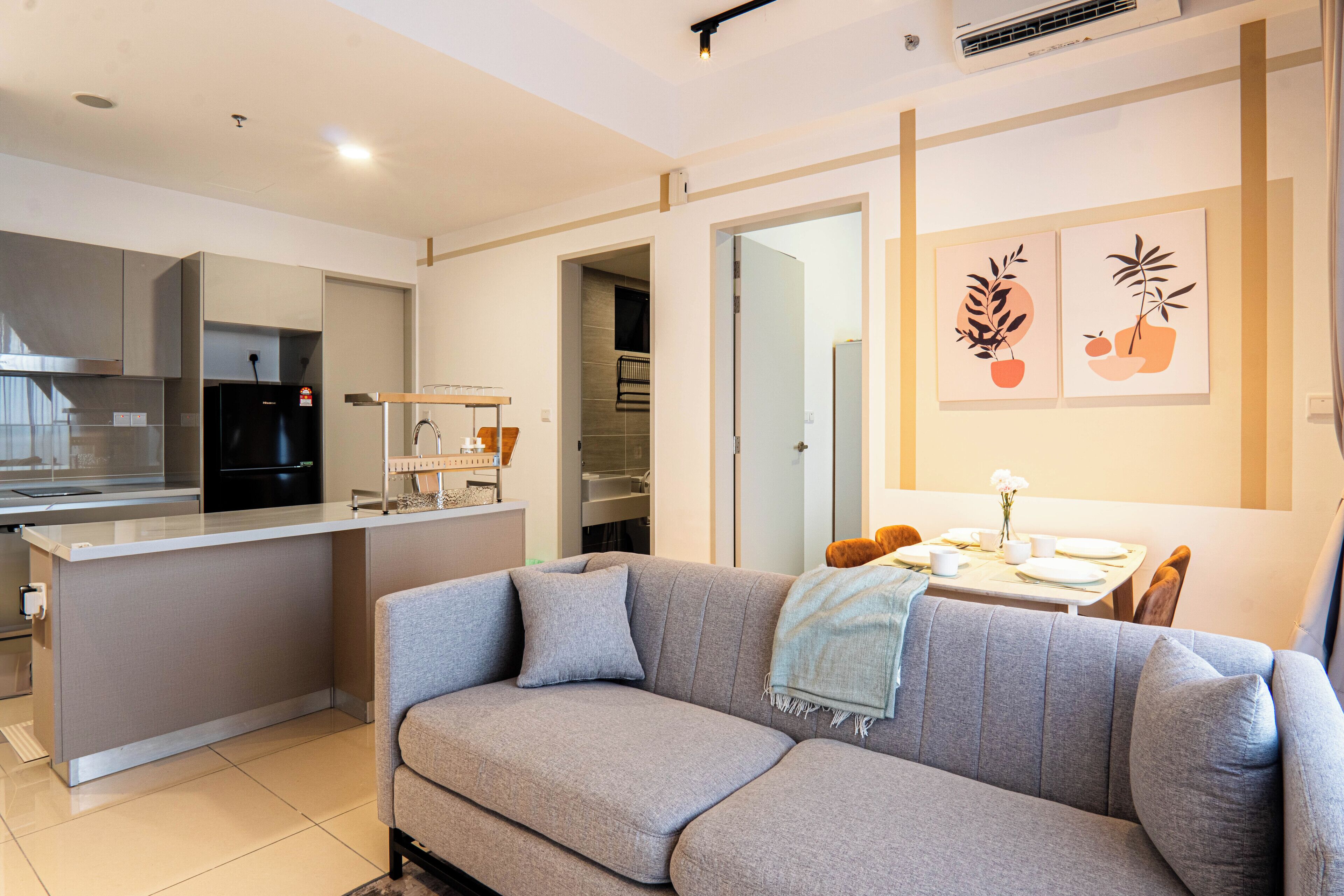 Una cocina moderna con un sofá gris, una mesa de comedor y un rincón de comedor pequeño.