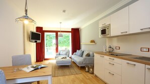 Una sala de estar moderna con un sofá, una mesa de comedor con sillas, una zona de cocina con armarios y un microondas, y un televisor.