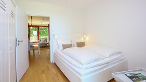 Un dormitorio con cama, mesita de noche y vistas al balcón.