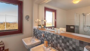 Une salle de bain avec deux lavabos, un grand miroir et une douche.