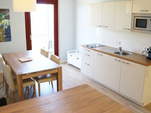 A modern kitchen with white cabinets, a wooden countertop, and a built-in microwave.