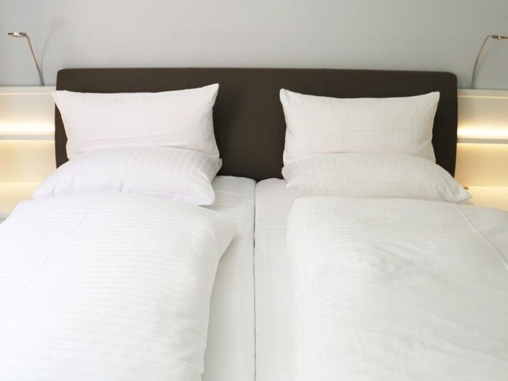 A double bed with white linens and a dark headboard.