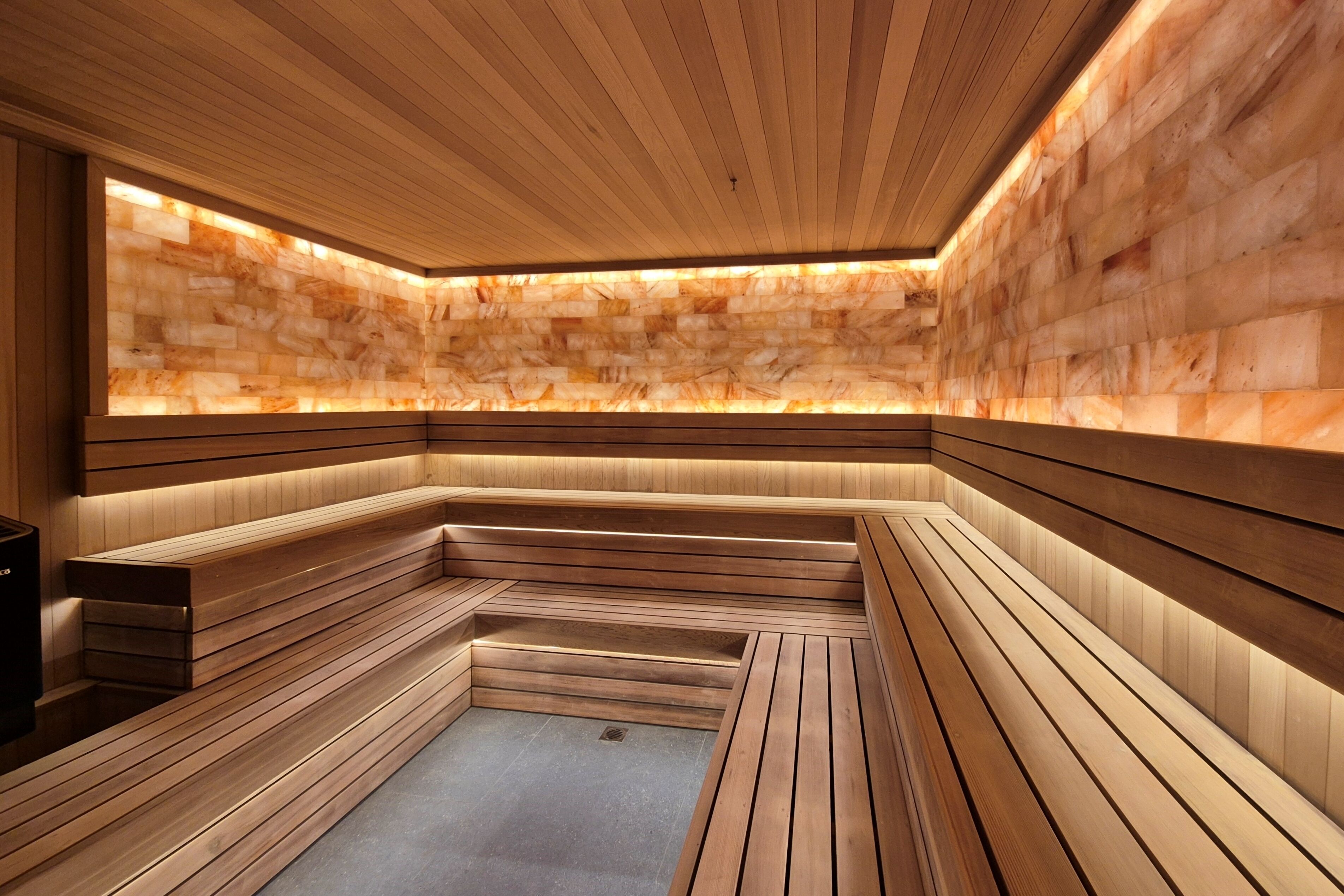 A sauna with wooden benches and a stone wall.