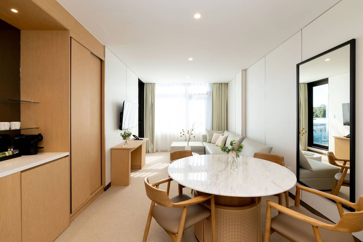Une chambre d’hôtel moderne dotée d’un coin repas, d’un canapé et d’un grand miroir.