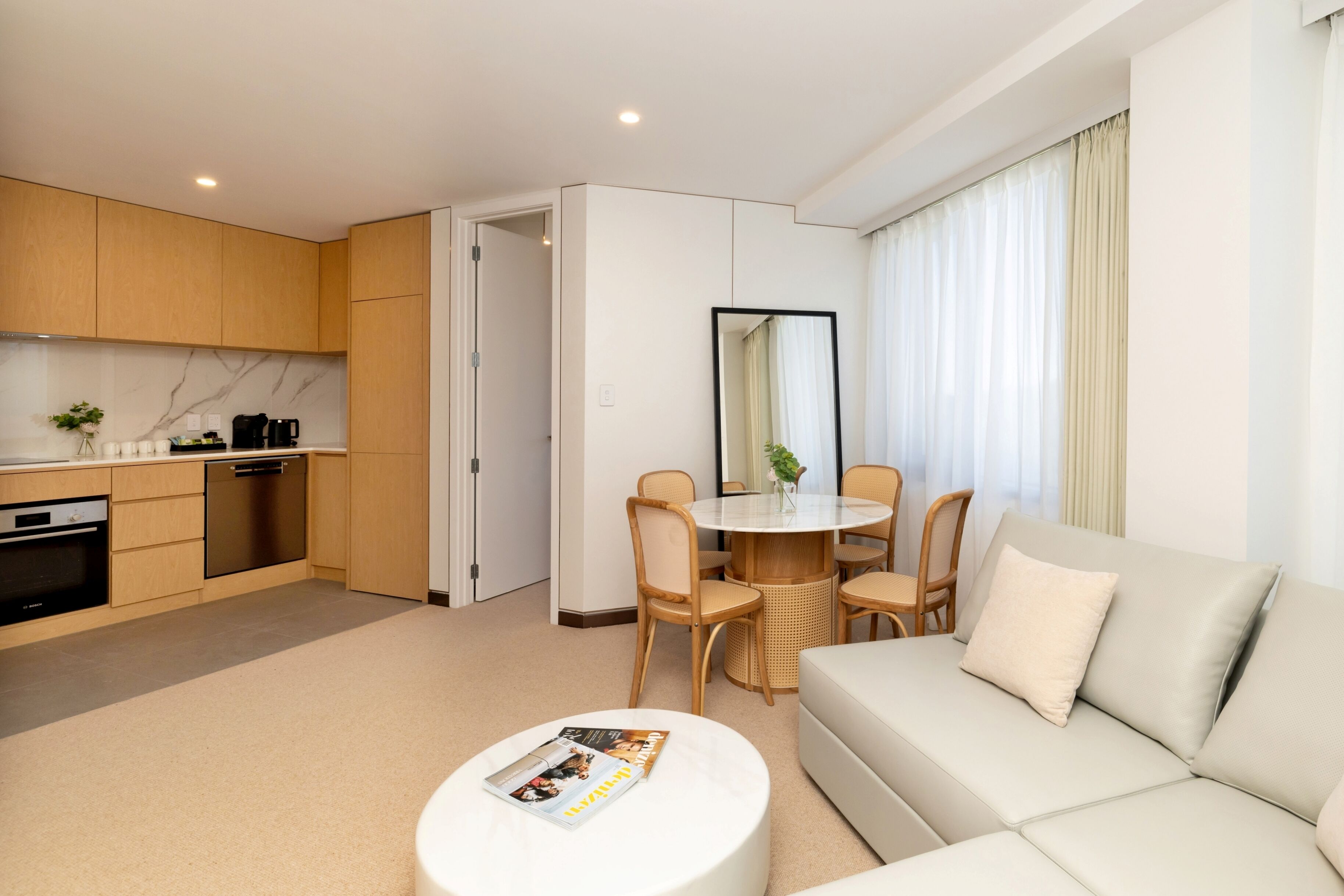 A modern hotel room with a kitchen, dining area, and living space.