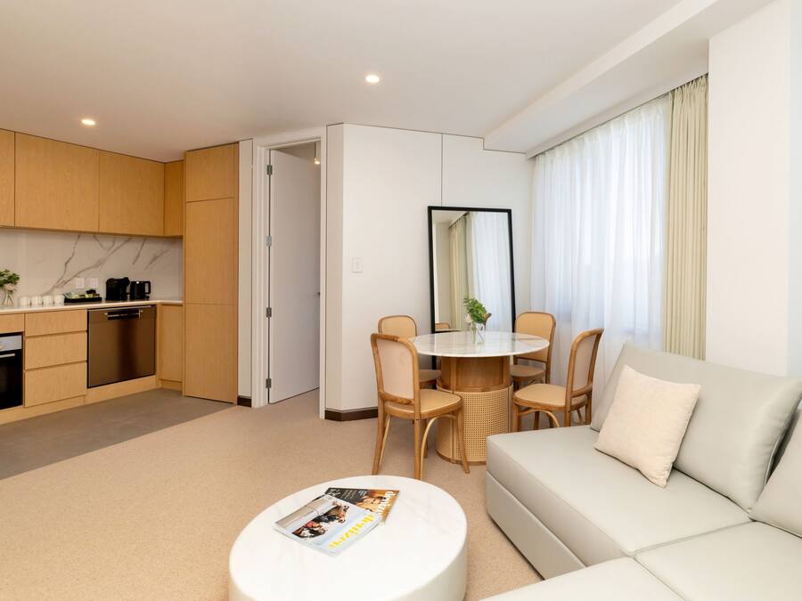 A modern hotel room with a kitchen, dining area, and living space.