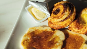 Um prato branco com três panquecas e um pequeno recipiente de manteiga.
