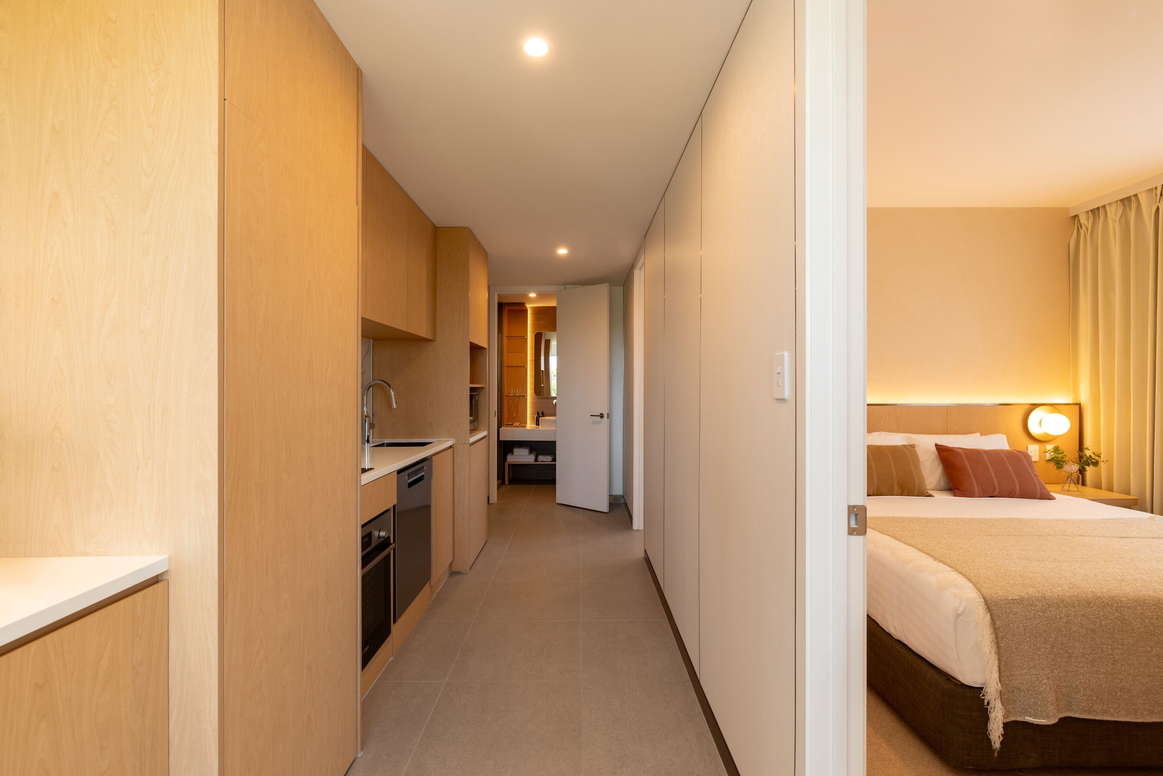 Una habitación de hotel con cama, mesita de noche y vistas al pasillo.
