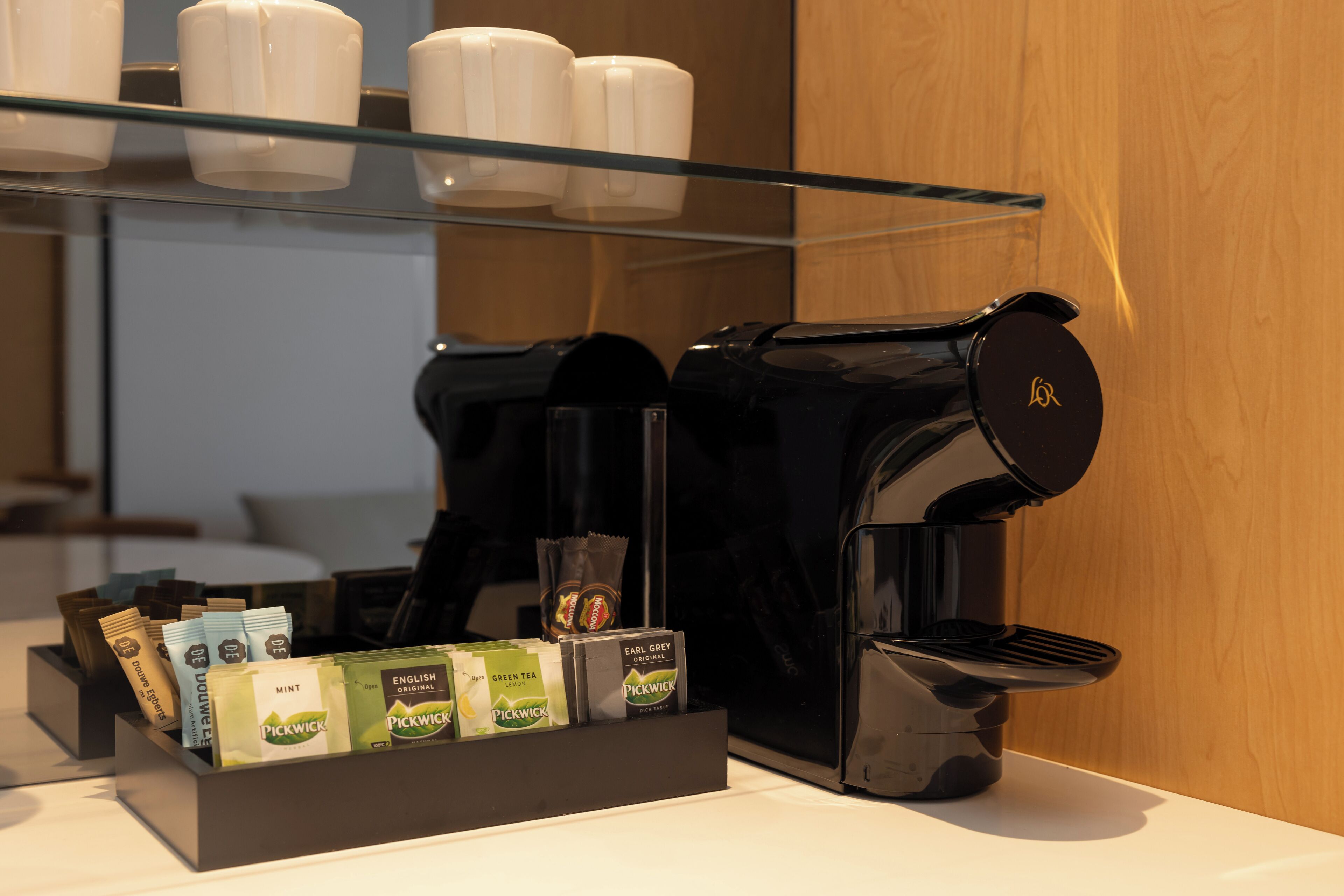 Une machine à café dotée d’un compartiment pour les capsules de café, contenant différentes marques et saveurs.