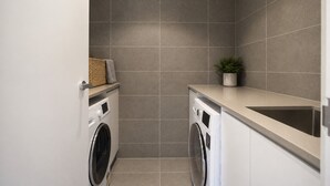 A compact laundry room with two washing machines, a countertop, and a sink. - The Evelyn Port Melbourne by Ready Set Stay - WIFI, linen, towels, brand new (Port Melbourne)