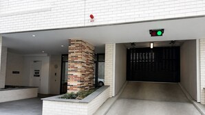 A modern building entrance with a brick pillar, a gated driveway, and a green traffic light. - The Evelyn Port Melbourne by Ready Set Stay - WIFI, linen, towels, brand new (Port Melbourne)