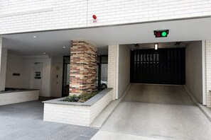 A modern building entrance with a brick pillar, a gated driveway, and a green traffic light. - The Evelyn Port Melbourne by Ready Set Stay - WIFI, linen, towels, brand new (Port Melbourne)