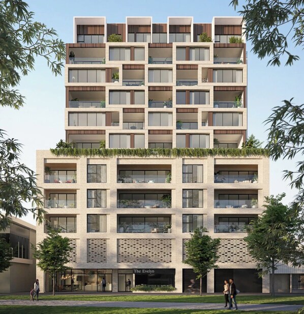 Ein mehrstöckiges Gebäude mit modernem Design, das Balkone mit Pflanzen, große Fenster und einen Eingang im Erdgeschoss mit der Aufschrift "The Evelyn" zeigt.