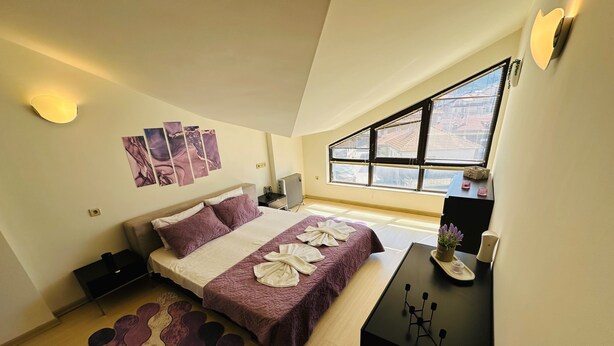 Una habitación de hotel moderna con una cama grande, un escritorio y una ventana con vistas a la ciudad.