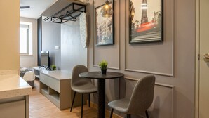 Una cocina moderna con comedor, que incluye una mesa redonda, dos sillas, una encimera y una tabla de surf colgada.
