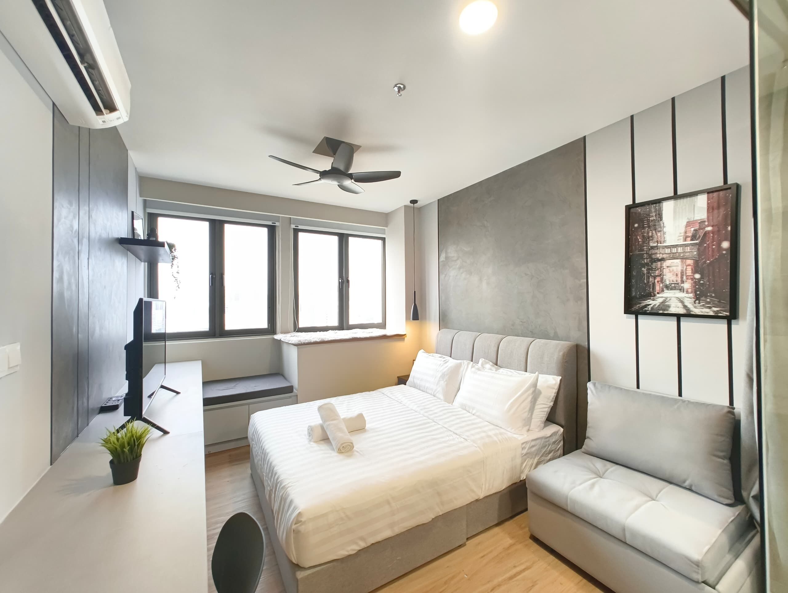 A modern bedroom with a bed, a sofa, a ceiling fan, and a window.