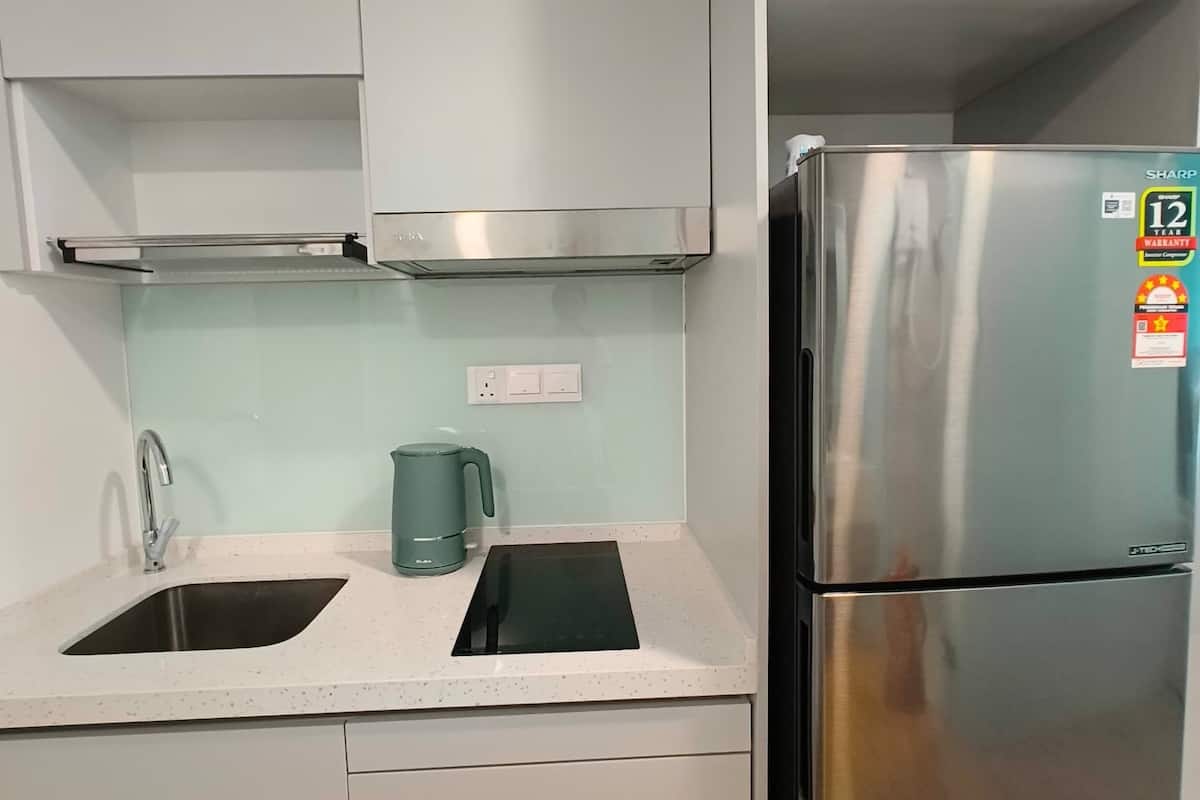 A modern kitchen with stainless steel appliances, a double sink, and a kettle.