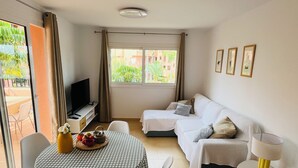 A cozy room with a checkered table, a sofa, a TV, and a balcony view. - Mediterranean View, in Mar Menor Golf Resort (Torre Pacheco)