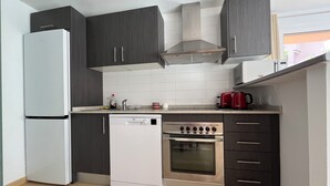 A compact kitchen with a built-in dishwasher, oven, and a red coffee maker on the countertop. - Mediterranean View, in Mar Menor Golf Resort (Torre Pacheco)