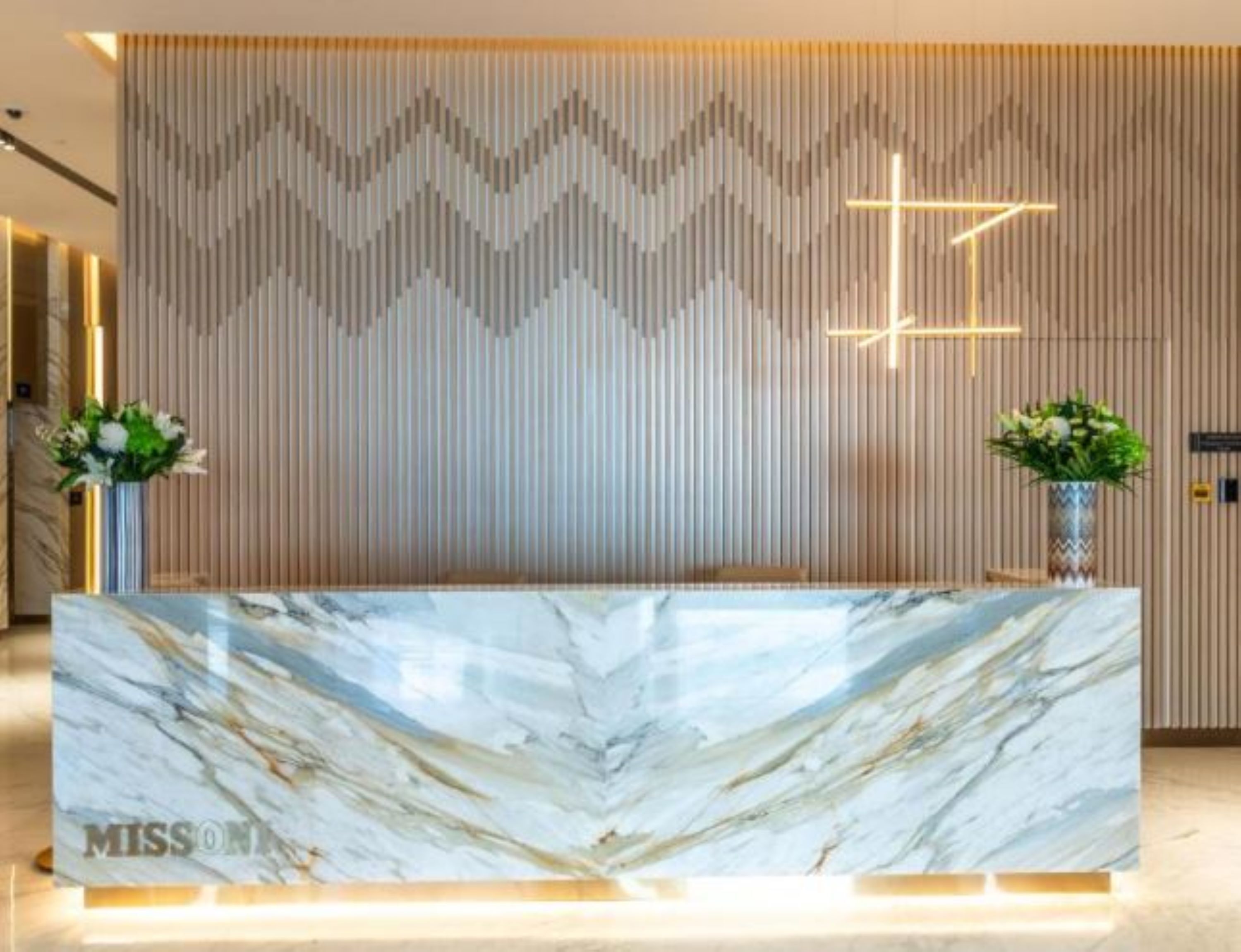A reception desk with a marble top and a cross on the wall behind it.