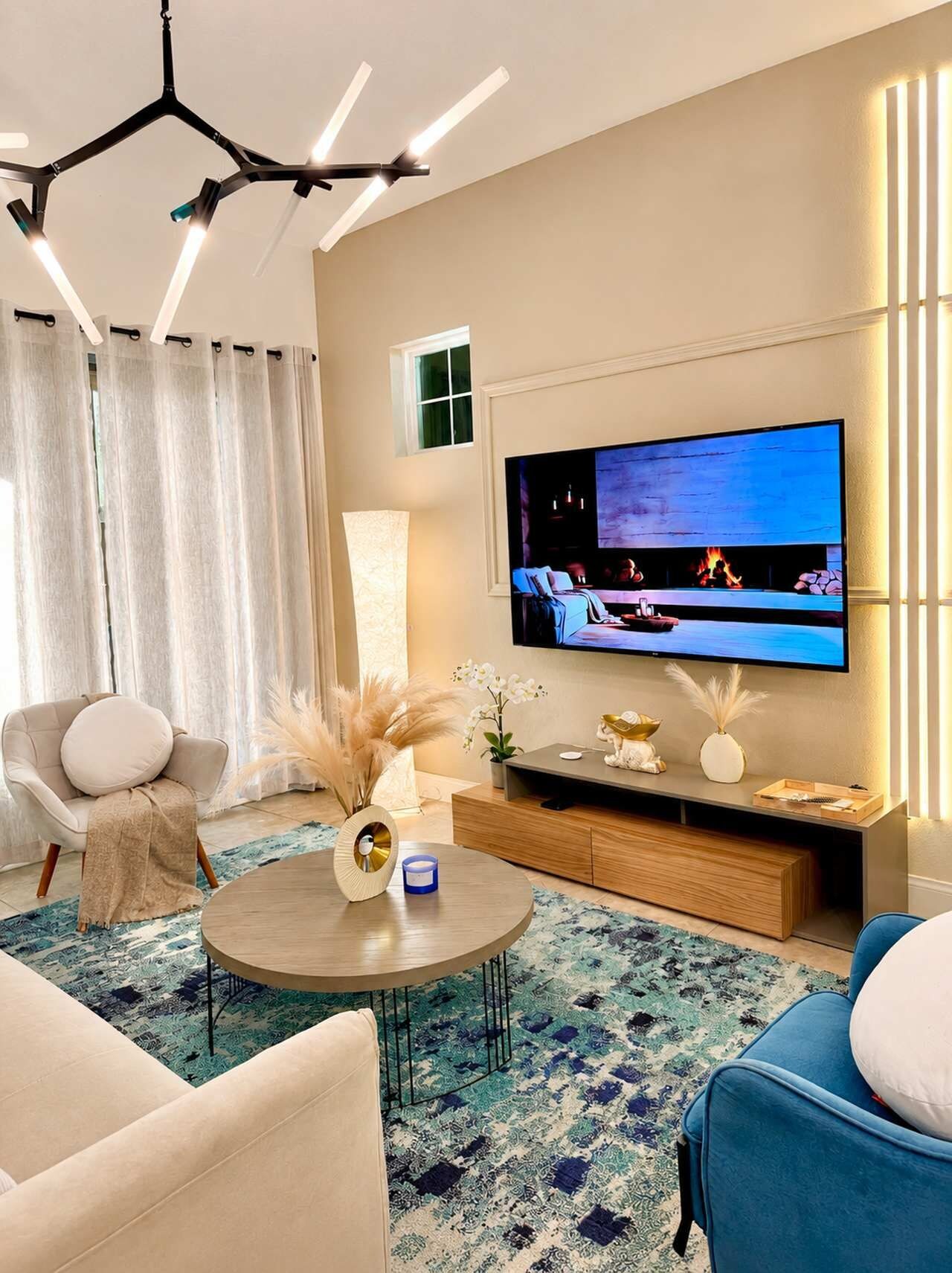 A modern living room with a flat-screen TV, a round coffee table, and a sofa.