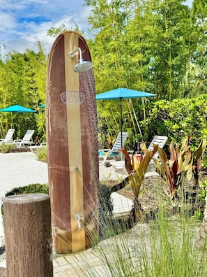 A wooden structure with a showerhead, surrounded by greenery and lounge chairs. - Magical Disney House With Private Pool (Davenport)