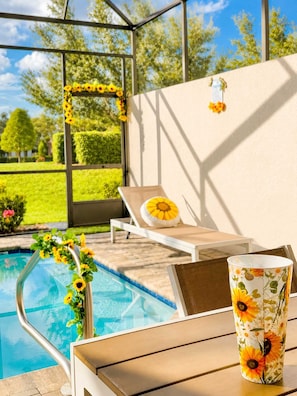 A poolside area with a lounge chair, a table, and a decorative flower arrangement. - Magical Disney House With Private Pool (Davenport)