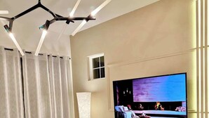 Un salon moderne avec un téléviseur à écran plat fixé au mur, une table basse ronde, un canapé et un fauteuil.
