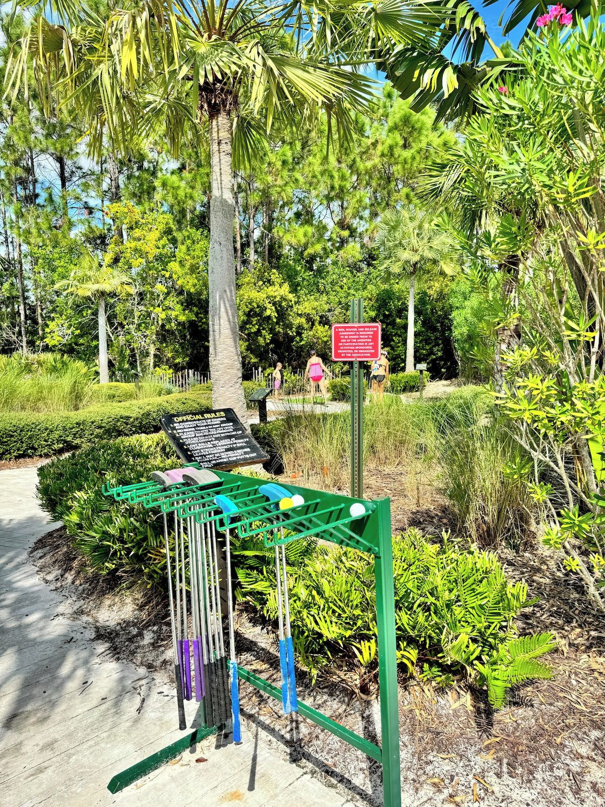 A green metal structure with a signboard, surrounded by lush greenery and a clear sky.