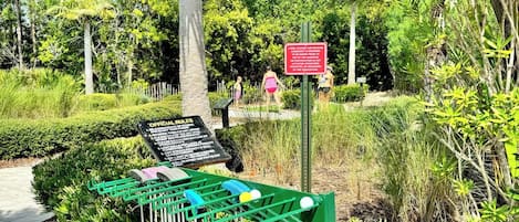 A green metal structure with a signboard, surrounded by lush greenery and a clear sky.