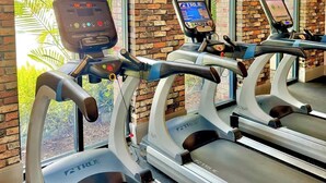 Une salle de sport équipée de tapis de course, d’un moniteur de fréquence cardiaque et d’un écran numérique.