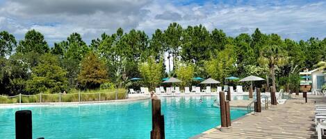 Un área de piscina con terraza empavedada, sillas de descanso y vistas a un área boscosa.