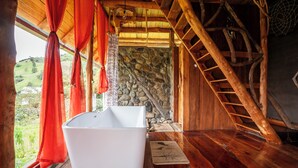 A rustic cabin interior with a stone wall, wooden staircase, and a bathtub. - Amanecer Andino (Rest cabin in the mountain) (Puyo)