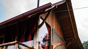 A rustic wooden house with a stone foundation, a chimney, and a balcony with red curtains. - Amanecer Andino (Rest cabin in the mountain) (Puyo)