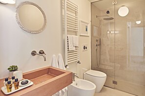 Ein modernes Badezimmer mit einem Holzwaschtisch, einem runden Spiegel, einer Duschkabine und einer Toilette.