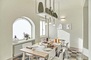Ein Essbereich mit großem Fenster, einem Heizkörper, einem Tisch gedeckt mit Tellern, Gläsern und verschiedenen Speisen.