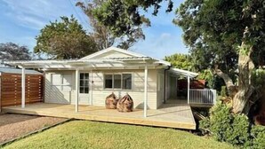 A single-story house with a covered porch, a fenced yard, and a small garden area. - Miami one one - Superior King Studio - Walk to Beach, Village and 2 Vineyards (Waiheke Island)