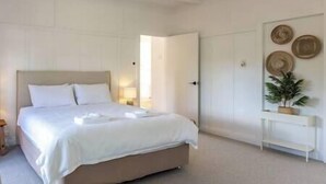A bedroom with a bed, bedside table, and a wall with decorative plates. - Miami one one - Superior King Studio - Walk to Beach, Village and 2 Vineyards (Waiheke Island)