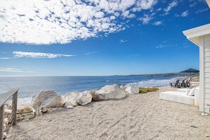 Une vue sur la plage avec un bâtiment blanc, un canapé blanc et une clôture en bois.