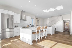 A modern kitchen with a central island, stainless steel appliances, and a staircase leading to another level.