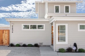A two-story house with a number 22806 on the side, a wooden gate, and a driveway.