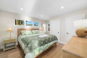 A bedroom with a bed, bedside tables, a lamp, and a door.