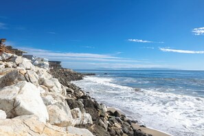 Une propriété située sur la côte, avec un rivage rocheux, une vue sur l’océan et des bâtiments modernes.
