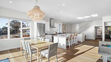 Une cuisine moderne avec des meubles blancs, un îlot central et un lustre suspendu.